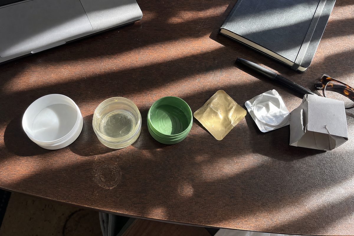 Six emptied patch jars and torn sachets lined up on a desk with their labels turned to the wall